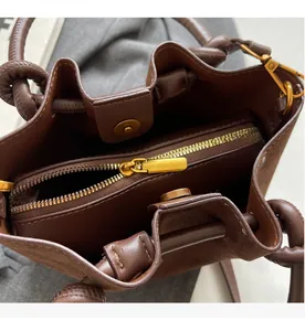 Detailed view of the brown bucket bag interior with a smooth gold zipper and magnetic closure