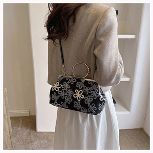 Détail du sac bandoulière vintage avec broderie florale et poignée en métal doré