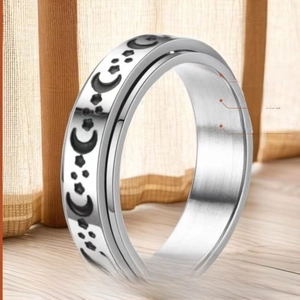 Minimalist silver stainless steel spinner ring with black moon pattern on wooden surface