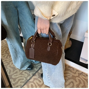 Nahaufnahme der braunen Lammfell-Boston-Tasche mit Ledergriffen und goldenen Akzenten