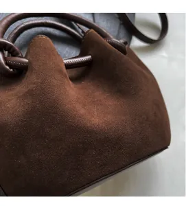 Detailed view of dark brown suede bucket bag texture and premium leather top handle