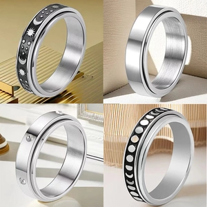 Detail view of four stainless steel spinner rings with moon, star, and zircon inlay designs