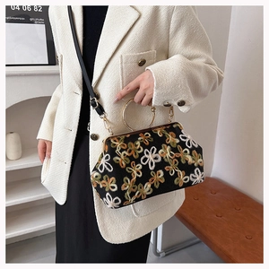 Détail d'une pochette de soirée vintage avec broderie florale et anse ronde dorée