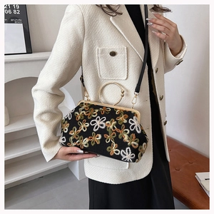Détail du sac brodé à fleurs avec poignée en anneau doré et fermeture à fermoir