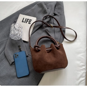 Detail view of coffee brown suede bucket bag texture on a grey suit jacket