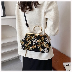 Détail d'un sac de soirée coquillage vintage avec broderies florales et fermoir doré