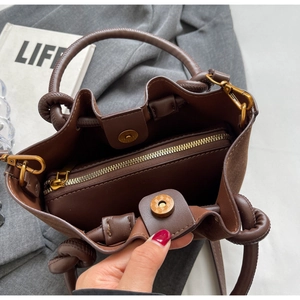 Detail view of brown bucket bag showing magnetic closure and interior zipped compartment