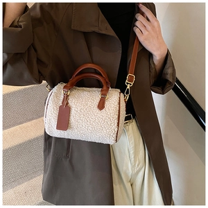 Fashionable beige plush Boston bag with brown leather accents worn by a model