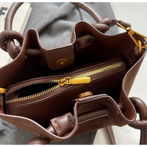 Detail of the inner magnetic closure and zipper compartment of a brown bucket bag