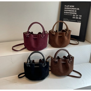 Detailed view of matte suede bucket bags in four colors arranged on marble steps