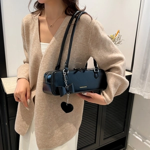 Minimalist black baguette shoulder bag with chic bow and metallic heart charm detail