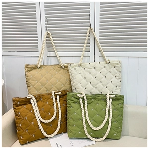 Close-up of four quilted tote bags with bow embroidery and cord handles in multiple colors