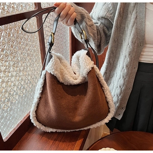 Detail of brown suede tote bag featuring white faux shearling trim and leather shoulder strap