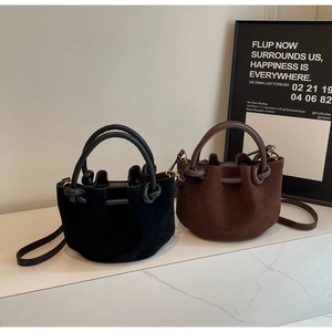 Detail of matte suede bucket bags in black and brown with knotted handles and drawstrings