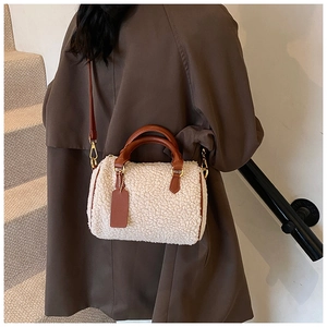 Detail of plush boston bag featuring cream faux fur texture and brown leather straps