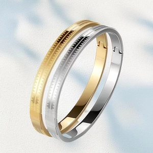 Detail of silver and gold stainless steel bracelets with geometric serrated etching