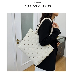Detail of cream white quilted tote bag with small brown bow embroidery and rope handle