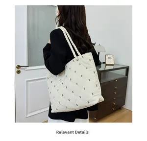 Close-up of white quilted tote bag with brown bow embroidery and rope handles