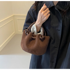 Close-up of vintage brown matte bucket bag with unique knotted handle and suede texture