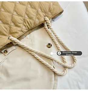 Detail of rope handles and bow embroidery on quilted khaki tote bag with metal rings