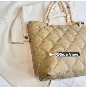 Side view of beige quilted tote bag featuring bow embroidery and thick rope handles