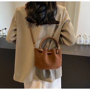 Close-up of retro brown matte bucket bag showing suede texture and twisted handle detail
