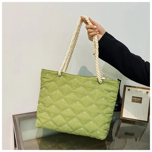 Detail view of quilted grass green tote bag featuring white bow embroidery and rope handles
