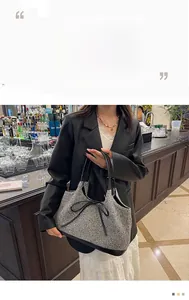 Detail of grey wool handbag featuring black leather trim and elegant bow accent