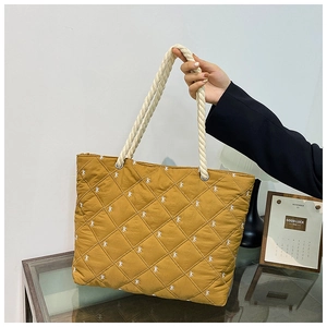 Detail of yellow quilted tote bag with bow embroidery and white cotton rope handle