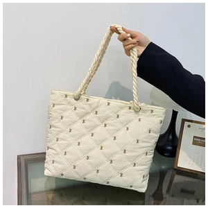 Close-up of quilted beige tote bag with embroidered bows and rope handles details