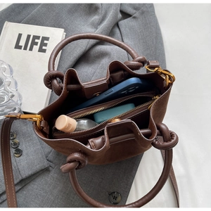 Detail of dark brown matte leather bucket bag showing inner zipper pocket and storage capacity