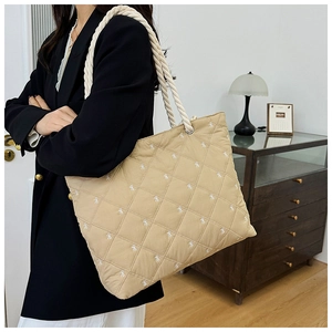 Detail of quilted canvas tote bag with bow embroidery and white cotton rope handle