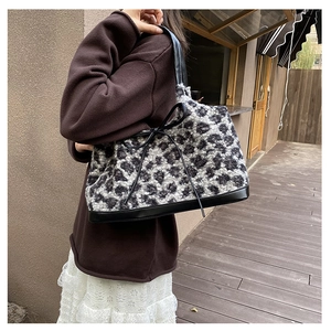 Detail of leopard print plush tote bag with bow accent and leather base shown on shoulder