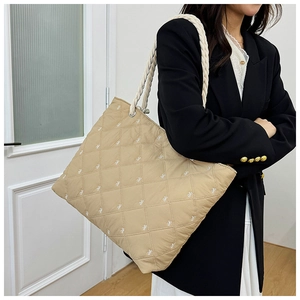 Detail of khaki quilted tote bag featuring bow embroidery and thick cotton rope shoulder strap