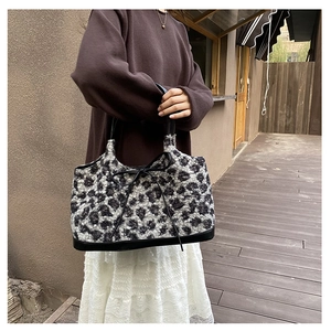 Close-up of leopard print faux fur tote bag with black bow detail and leather handles