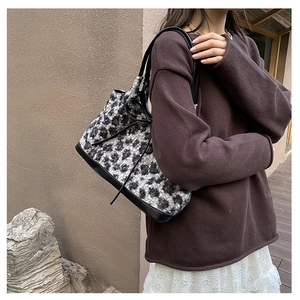 Detailed view of plush leopard print shoulder bag with leather handles and side straps