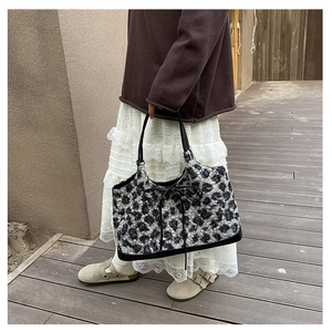 Detail of plush leopard print tote bag with black bow and elegant faux fur texture