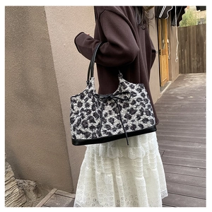 Close-up of leopard print plush handbag with black leather bow and handle detail
