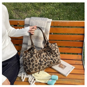 Detail of leopard print plush tote bag with brown leather handles and decorative bow