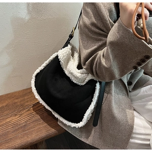 Détail du sac à épaule en daim noir avec bordure en fausse fourrure blanche et boucle