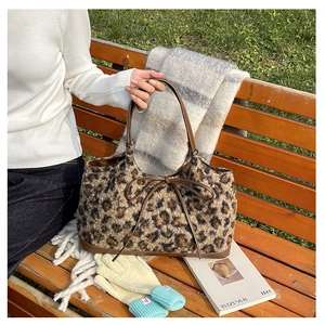 Detail view of plush leopard print tote bag with brown leather handles and bow decoration