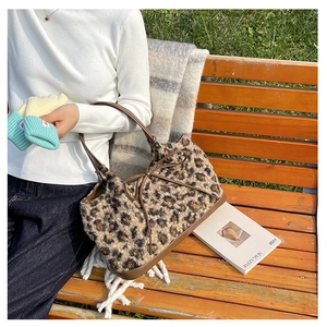 Detail of plush leopard print tote bag with brown leather handles and bow decoration