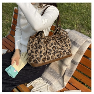 Detail showing plush leopard print texture and brown leather bow on the tote bag