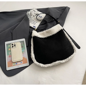 Détail d'un sac en daim noir avec bordure en fausse fourrure blanche sur un blazer