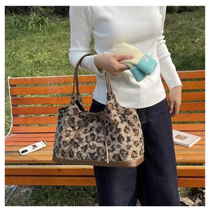 Detail of plush leopard print tote bag with brown leather bow and strap design