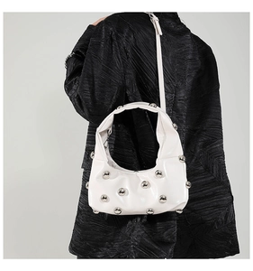 Detail of white moon bag with silver studs worn over a black textured jacket