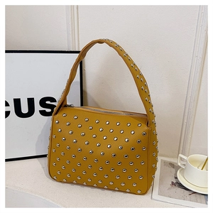 Macro detail of yellow pebbled leather handbag featuring silver metal rivets and texture
