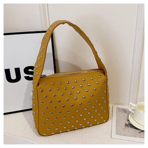 Detail of mustard yellow rivet shoulder bag with silver studs and lychee texture