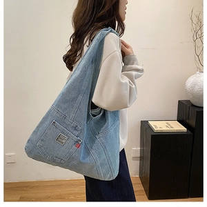 Détail du sac cabas en jean délavé bleu avec badge BDG et grande poche frontale