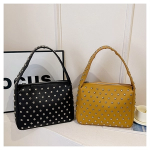 Detail view of black and yellow faux leather handbags with heavy metal rivet decorations